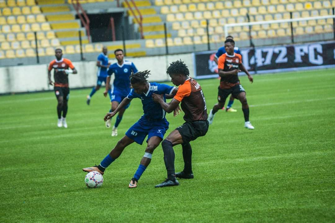 Rovers FC players in blue and white battling with the ball against 1472 FC players in orange and black in their 2023/2024 NNL game at the Mobolaji Johnson Arena, Lagos on Sunday 26 Nov 2023